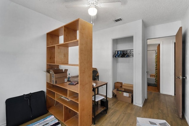 1905 Chestnut Ave, Austin, TX 78722 - bedroom featuring wood finished floors, a textured ceiling, a closet, and a ceiling fan