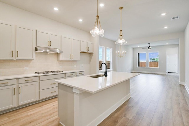 1409 S Brook Dr, Leander, TX 78641 - kitchen featuring gas stovetop, light wood-style floors, under cabinet range hood, decorative backsplash, and recessed lighting