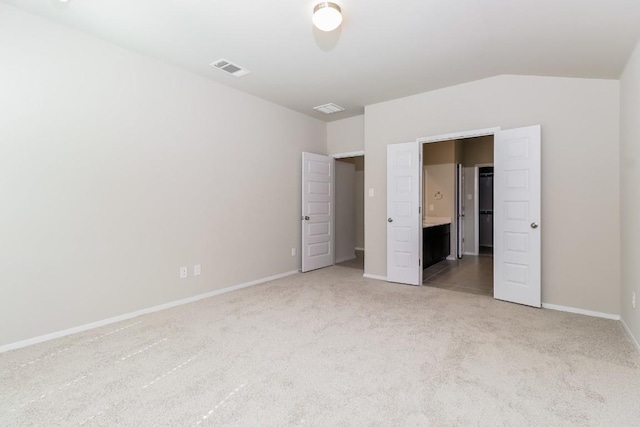 20411 Rockpark Ln, Lago Vista, TX 78645 - unfurnished bedroom featuring light carpet, vaulted ceiling, and connected bathroom