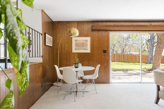 dining space featuring carpet flooring and wood walls