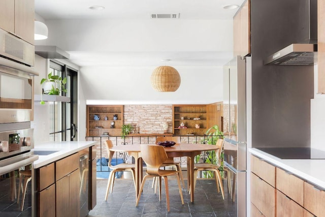kitchen featuring visible vents, light countertops, wall oven, and wall chimney exhaust hood