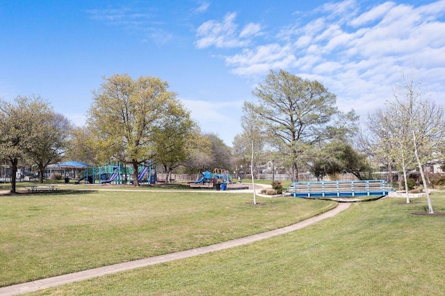 view of community featuring playground community, fence, and a lawn