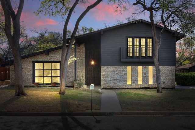 view of front facade with stone siding and a yard