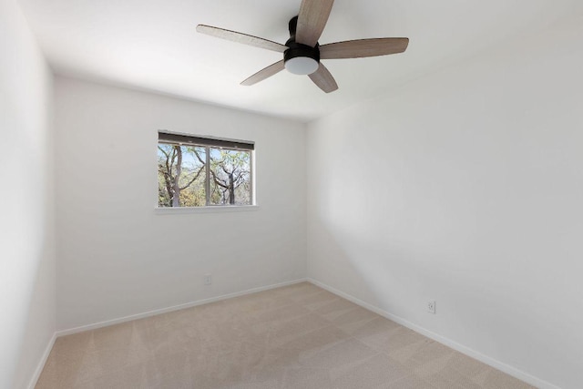 empty room with a ceiling fan, light carpet, and baseboards
