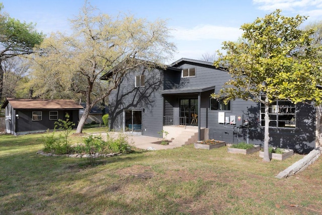 view of front of house featuring a front yard, an outdoor structure, a patio, and a garden