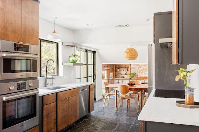 kitchen featuring light countertops, a sink, brown cabinetry, stainless steel appliances, and visible vents