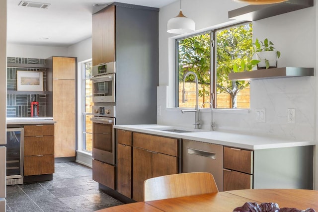 kitchen featuring light countertops, a sink, beverage cooler, visible vents, and decorative backsplash