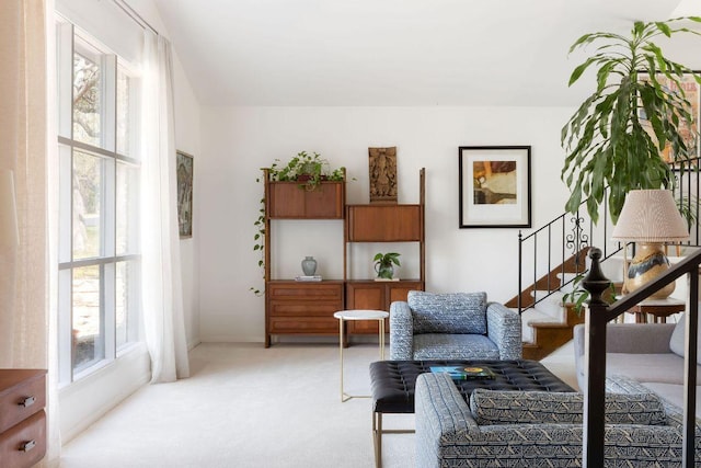 sitting room featuring stairway and light carpet