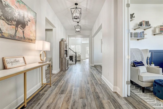 212 Tovas Secret Cv, Georgetown, TX 78628 - hallway featuring baseboards, stairs, wood finished floors, and an inviting chandelier