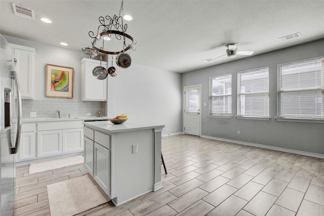 1813 Artesian Springs Xing, Leander, TX 78641 - kitchen with backsplash, white cabinetry, light countertops, a center island, and ceiling fan