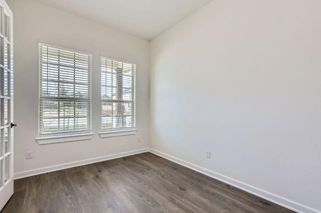 unfurnished room featuring dark wood-style floors and baseboards