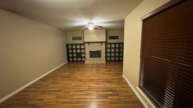 unfurnished living room with visible vents, baseboards, a fireplace, wood finished floors, and a ceiling fan