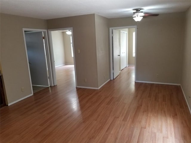 spare room with baseboards, light wood-style flooring, and a ceiling fan