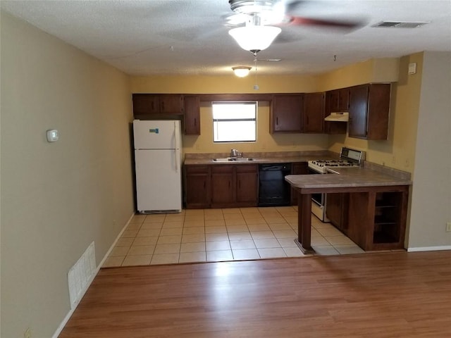 kitchen with a sink, freestanding refrigerator, dishwasher, visible vents, and range with gas cooktop