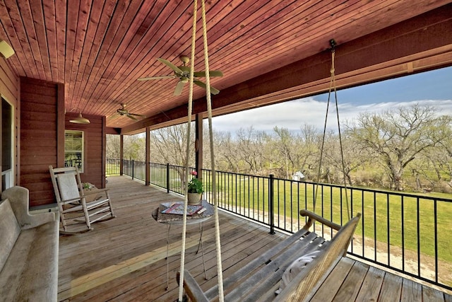 wooden terrace featuring a yard and a ceiling fan