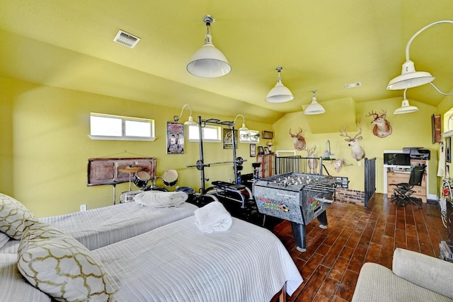 bedroom featuring wood finished floors, lofted ceiling, and visible vents