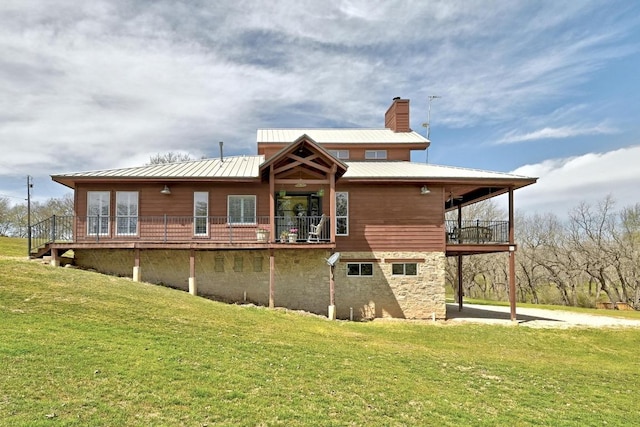 rear view of house featuring a balcony, metal roof, a chimney, and a yard