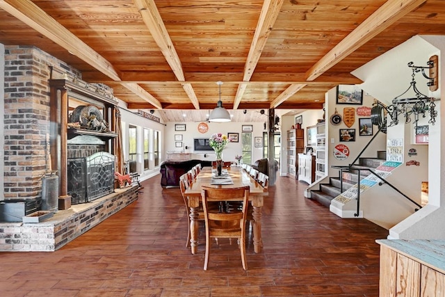 dining room featuring stairs, dark wood-style flooring, wooden ceiling, beamed ceiling, and a fireplace