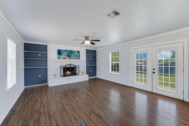 155 Travis Ln, Spicewood, TX 78669 - unfurnished living room with ornamental molding, healthy amount of natural light, dark wood-style flooring, a ceiling fan, and a brick fireplace