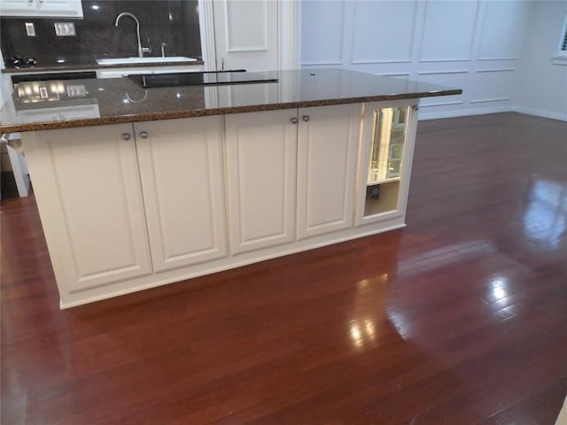 3501 Greystone Dr Unit 3501, Austin, TX 78731 - kitchen featuring black electric stovetop, a decorative wall, dark wood-style flooring, white cabinets, and dark stone countertops