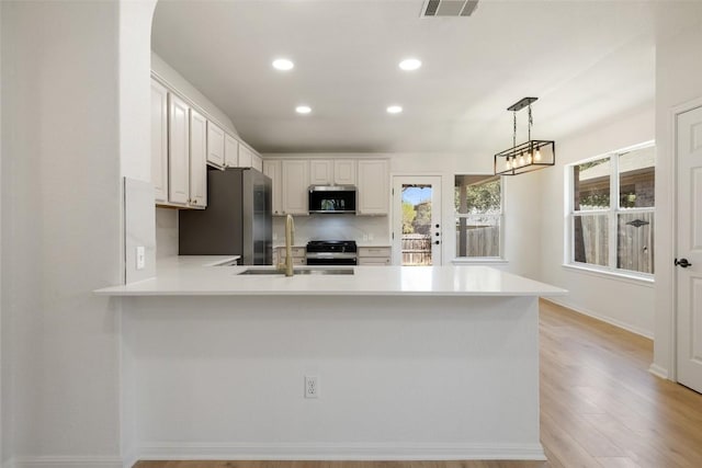 471 Bayou Bend Dr, Buda, TX 78610 - kitchen with freestanding refrigerator, a peninsula, light countertops, a sink, and recessed lighting