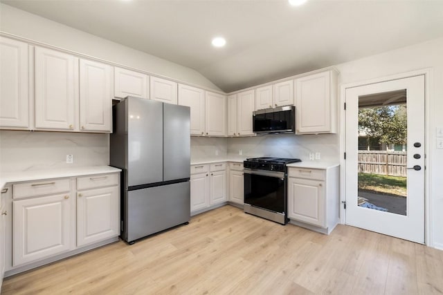471 Bayou Bend Dr, Buda, TX 78610 - kitchen featuring appliances with stainless steel finishes, light countertops, light wood-type flooring, white cabinets, and lofted ceiling