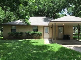ranch-style home with a carport, driveway, and a front yard