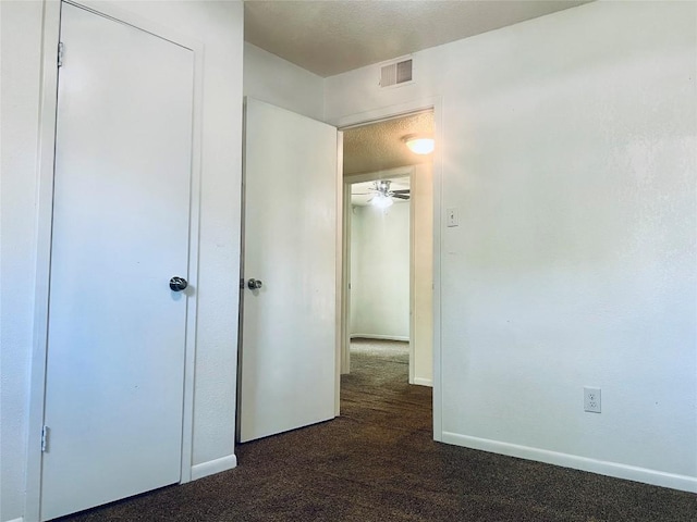 unfurnished bedroom featuring dark colored carpet, visible vents, and baseboards