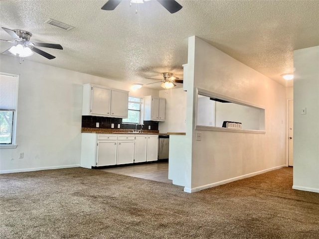 kitchen featuring a textured ceiling, stainless steel dishwasher, a ceiling fan, and carpet