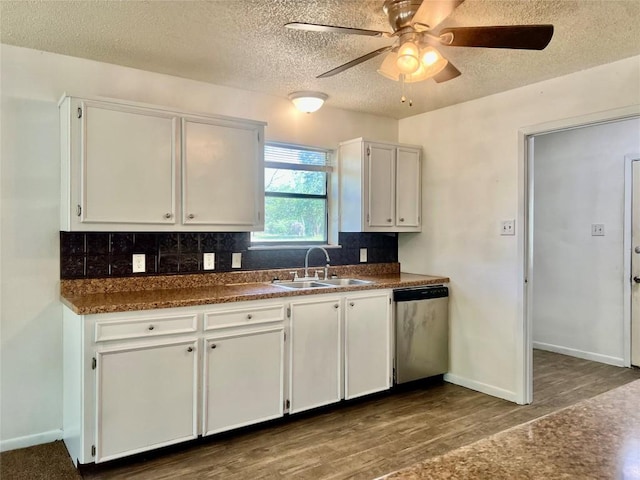 kitchen featuring a textured ceiling, white cabinetry, dark countertops, dishwasher, and a sink