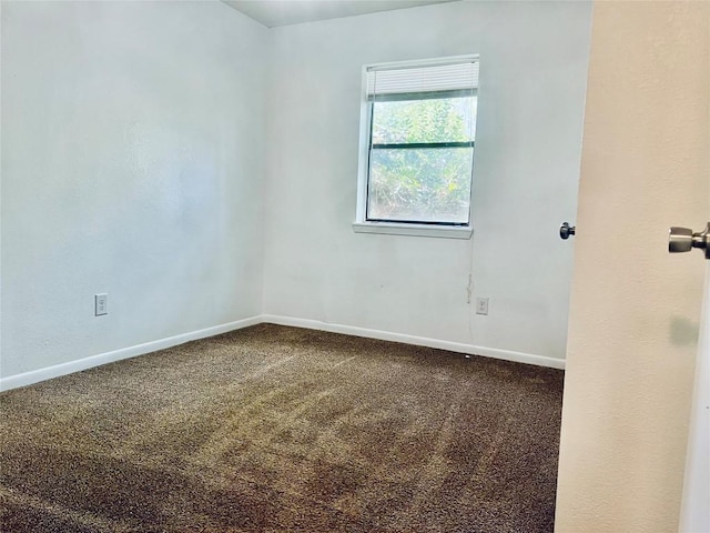 unfurnished room featuring dark carpet and baseboards