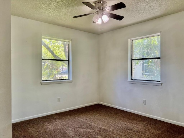 unfurnished room with baseboards, a textured ceiling, dark carpet, and ceiling fan