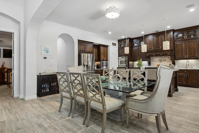 3801 Panther Hall, Leander, TX 78641 - dining space featuring arched walkways, light wood-style flooring, recessed lighting, ceiling fan, and crown molding