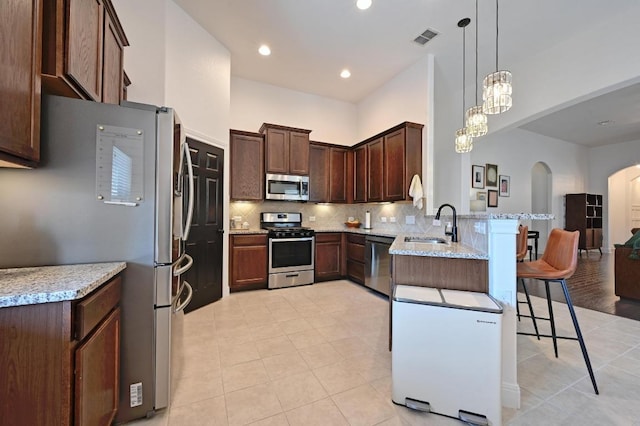 1909 Bobbywoods Ln, Manchaca, TX 78652 - kitchen featuring visible vents, a peninsula, arched walkways, light tile patterned floors, and stainless steel appliances