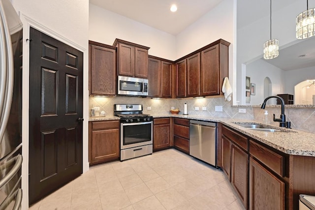1909 Bobbywoods Ln, Manchaca, TX 78652 - kitchen featuring backsplash, light stone countertops, appliances with stainless steel finishes, and a sink