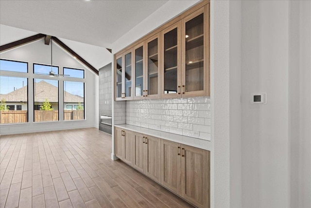 18716 Hopper Ln, Austin, TX 78738 - interior space with glass insert cabinets, wood finished floors, lofted ceiling with beams, light countertops, and decorative backsplash