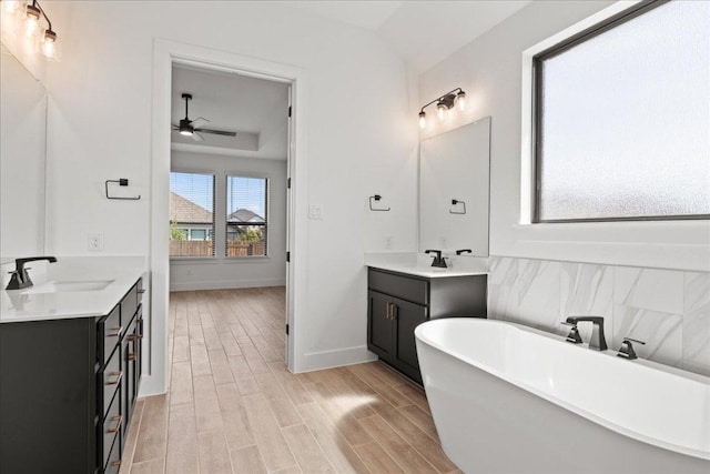 18716 Hopper Ln, Austin, TX 78738 - full bath featuring wood finished floors, a sink, two vanities, a freestanding tub, and ceiling fan