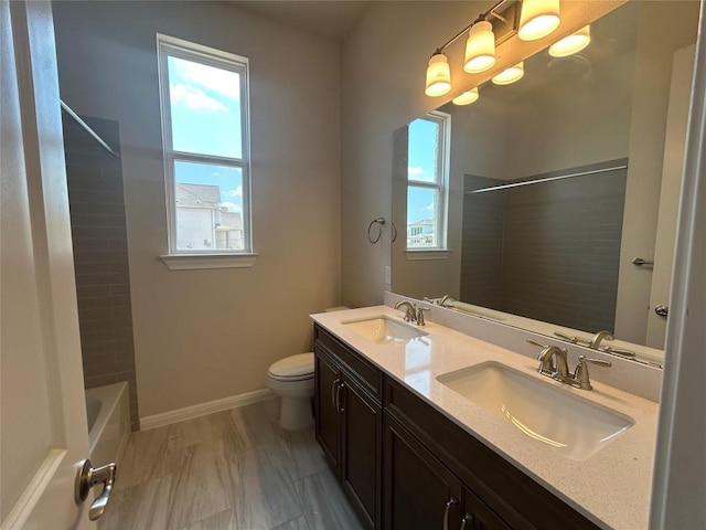 8217 Grenadier Dr, Austin, TX 78738 - bathroom with double vanity, toilet, bathtub / shower combination, baseboards, and marble look tile flooring
