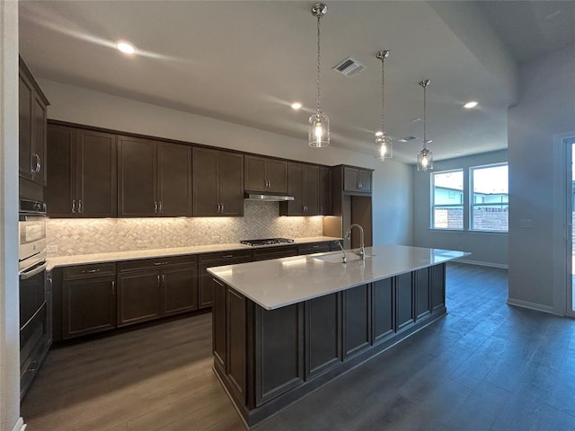 8217 Grenadier Dr, Austin, TX 78738 - kitchen featuring a sink, dark wood-style floors, under cabinet range hood, backsplash, and stainless steel gas cooktop