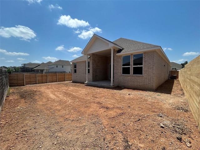 8217 Grenadier Dr, Austin, TX 78738 - back of property with brick siding, a fenced backyard, a patio area, a shingled roof, and cooling unit