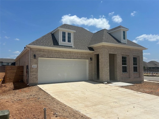8217 Grenadier Dr, Austin, TX 78738 - view of front of house with brick siding, driveway, a garage, and a shingled roof