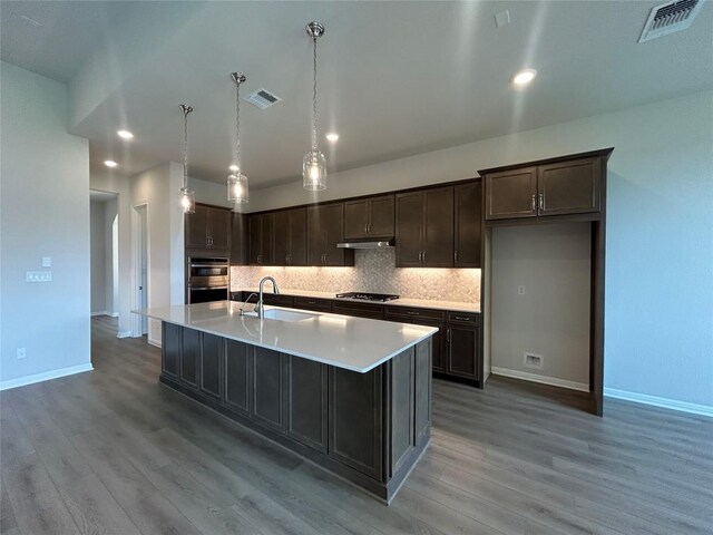 8217 Grenadier Dr, Austin, TX 78738 - kitchen featuring gas stovetop, backsplash, dark brown cabinets, light wood-type flooring, and recessed lighting