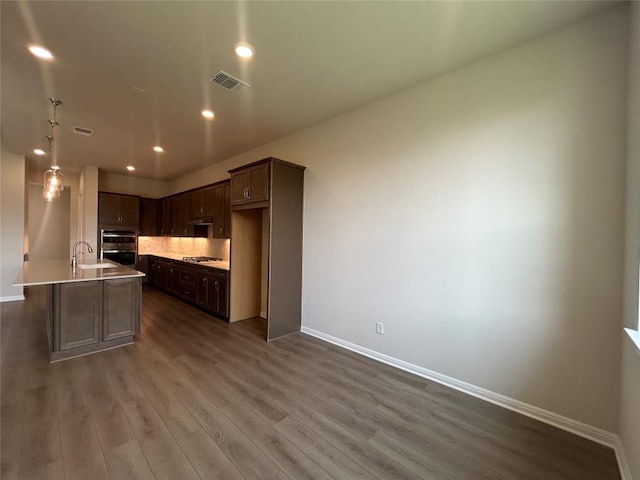 8217 Grenadier Dr, Austin, TX 78738 - kitchen featuring stainless steel appliances, dark wood-type flooring, recessed lighting, decorative backsplash, and dark brown cabinets