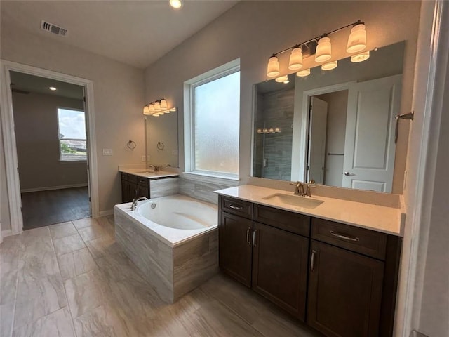 8217 Grenadier Dr, Austin, TX 78738 - full bathroom featuring a garden tub, two vanities, and tiled shower