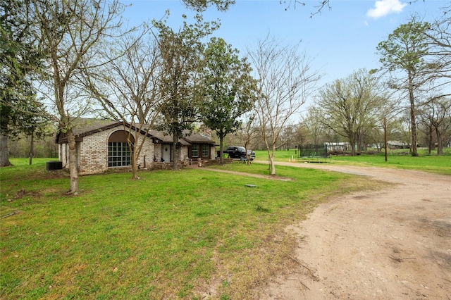 view of front of property featuring driveway, a front yard, and brick siding
