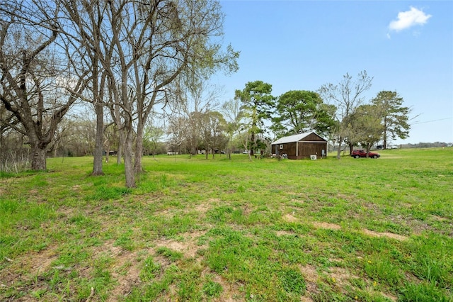 view of yard featuring an outdoor structure, a pole building, and a rural view