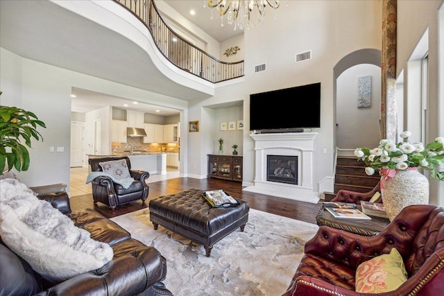 1600 Morning Moon Cir, Austin, TX 78732 - living room with a chandelier, a glass covered fireplace, a towering ceiling, light wood-type flooring, and arched walkways