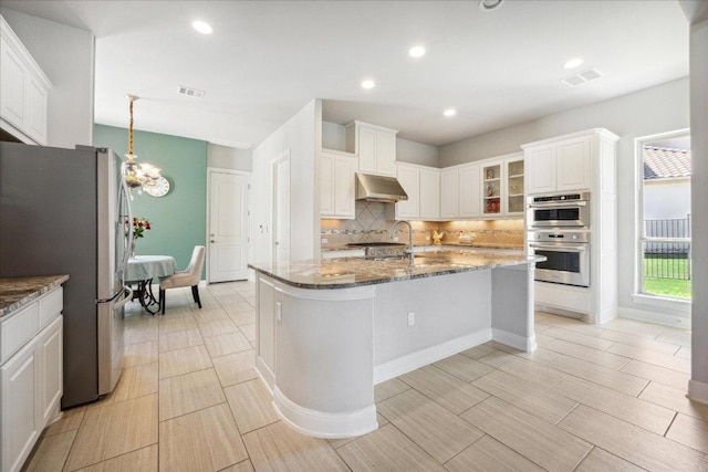 1600 Morning Moon Cir, Austin, TX 78732 - kitchen featuring stainless steel appliances, decorative backsplash, dark stone countertops, exhaust hood, and white cabinetry