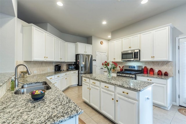 351 Still Hollow Crk, Buda, TX 78610 - kitchen with appliances with stainless steel finishes, a sink, a kitchen island, light tile patterned flooring, and decorative backsplash