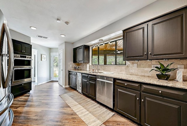409 Hurst Creek Rd, Lakeway, TX 78734 - kitchen featuring stainless steel appliances, a sink, backsplash, baseboards, and light stone counters
